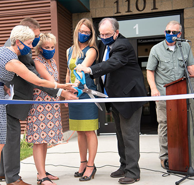 Longfellow Ribbon Cutting - Group of professionals cutting a ribon with gian scisors